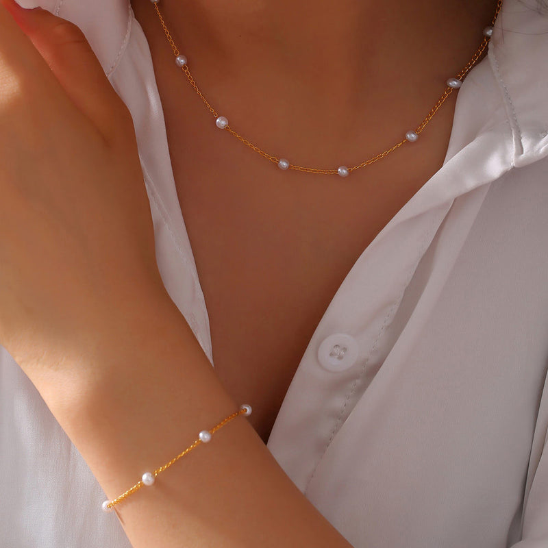 woman wearing a gold chain necklace and bracelet with pearl accents